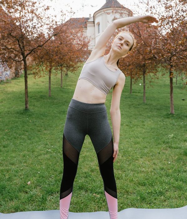 Woman in a dynamic yoga pose against a dark background with sage green accents.